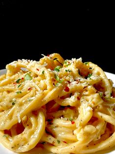 a white plate topped with pasta covered in parmesan cheese and garnished with green onions