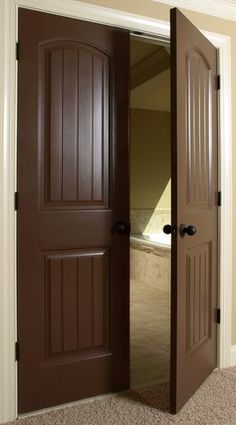 an open brown door in the middle of a room with carpet on the floor and walls