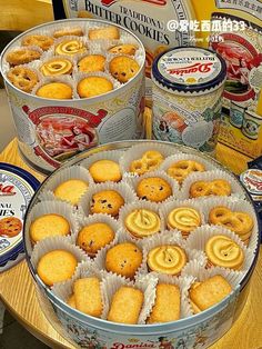 several tins filled with cookies on top of a table next to boxes of biscuits