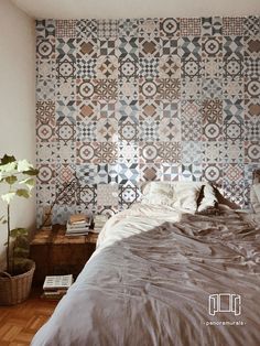 a bed sitting under a window next to a wall covered in decorative tiles and pillows