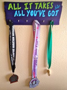 three medals hanging on a wall with an all it takes sign in the background that says, all you've got