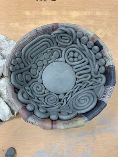 a clay bowl sitting on top of a wooden table next to rocks and paper towels