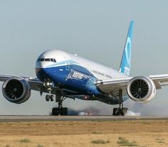 a blue and white jet airliner taking off from an airport runway with it's landing gear down