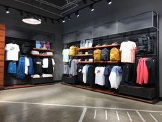 the inside of a clothing store with clothes on shelves