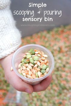 a person holding a small plastic bowl filled with nuts and seeds, text overlay reads simple scooping and pouring sensory bin