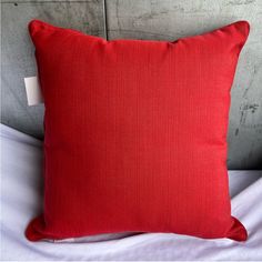 a red pillow sitting on top of a bed