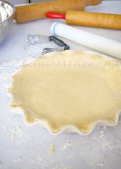 an uncooked pie crust sitting on top of a table next to baking utensils