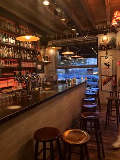 an empty bar with stools and bottles on the shelves