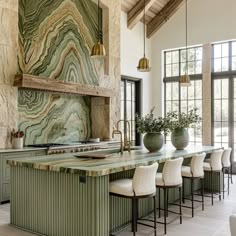 a large kitchen with marble counter tops and green cabinets, along with bar stools