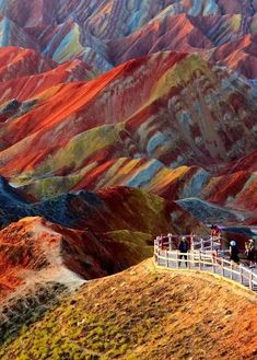 people standing at the top of a hill with colorful mountains in the background