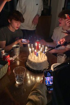 a group of people sitting around a table with a cake on it and lit candles