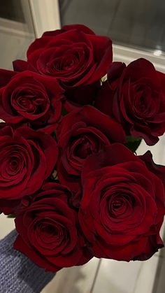 a vase filled with red roses on top of a table