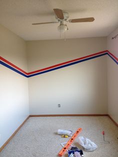 an empty room with some tools on the floor and a ceiling fan in the corner