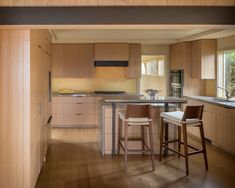 an open kitchen with wooden cabinets and stools