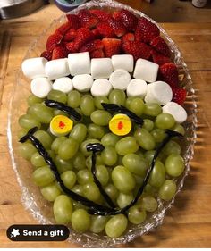 a bowl filled with grapes and marshmallows in the shape of a face