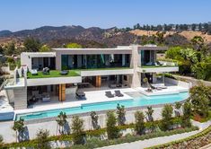 an aerial view of a house with a pool and lounge chairs in the foreground