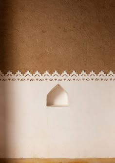 a white lamp sitting on top of a wooden table next to a wall with a brown background