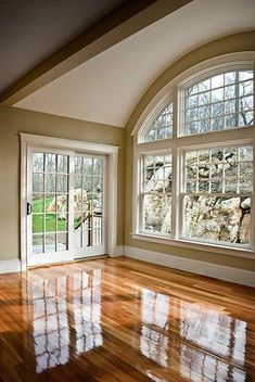 an empty room with wood floors and large windows