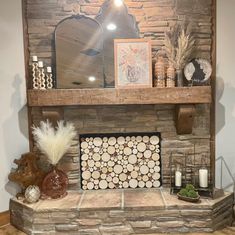 a stone fireplace with logs, candles and pictures on the mantel above it in a living room