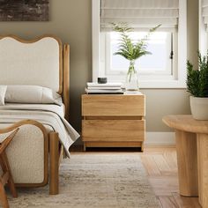 a bed sitting next to a window in a bedroom under a painting on the wall