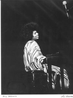 a black and white photo of a woman sitting at a piano