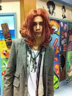 a man with long red hair wearing a jacket and tie standing in front of lockers