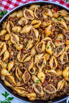 a skillet filled with pasta and ground beef on top of a checkered table cloth