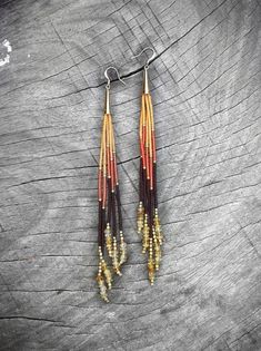 two pairs of earrings with beads hanging from them on top of a piece of wood