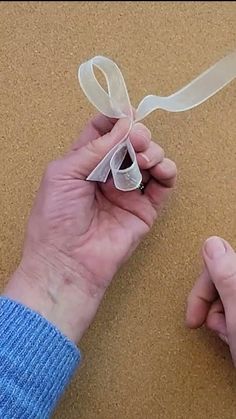 a person holding something in their hand with a ribbon tied around the end of it