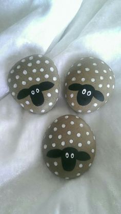 three painted rocks with sheep faces on them