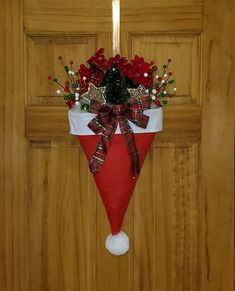 a red and white christmas stocking hanging on a wooden door with poinsettis