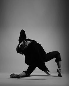 a man in black shirt and pants doing a handstand on one leg with his head down