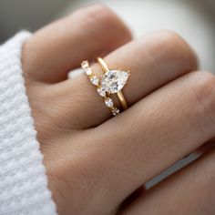 a woman's hand wearing a gold ring with two diamonds on top of it