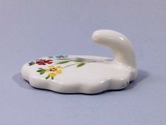 a white ceramic duck with colorful flowers on it's body and neck, sitting on a blue surface