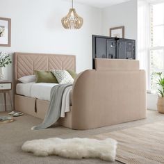 a bed sitting in the middle of a living room next to a window and rug