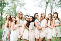 a group of young women standing next to each other in front of trees and grass