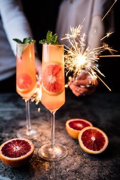 two champagne flutes filled with grapefruit and sparklers