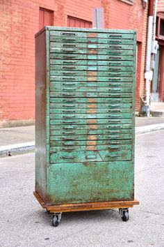 an old green metal box sitting on wheels