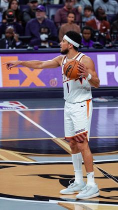 a man holding a basketball in his right hand and pointing to the side while standing on a court