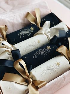 three wrapped presents are in a pink box with gold ribbons and stars on the wrapping paper