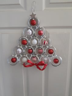 a christmas tree made out of cans is hanging on the front door with red and white ornaments