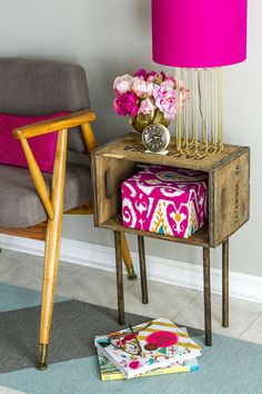 a pink lamp sitting on top of a wooden table next to a chair and ottoman