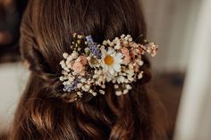 a close up of a woman with flowers in her hair and wearing a flower comb