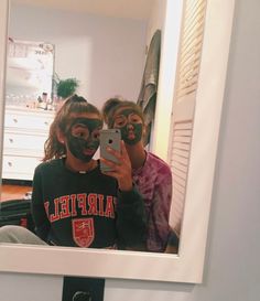 two people with face paint are taking a selfie in the reflection of a mirror