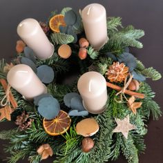 a christmas wreath with candles, oranges and other decorations