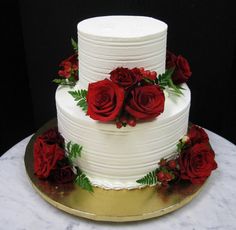 a three layer white cake with red roses on top