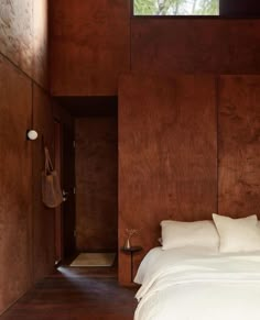 a bedroom with wood paneling and white bedding