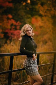 a woman leaning on a rail posing for the camera with her hands on her hips