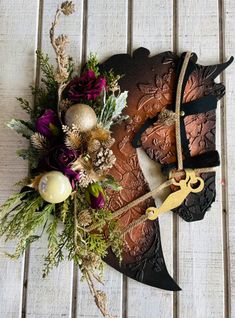 a piece of metal with some flowers and decorations on it's side next to a pair of scissors