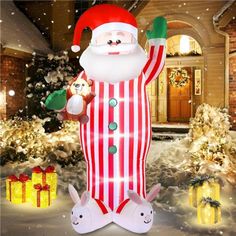 an inflatable santa clause standing next to christmas presents on the snow covered ground